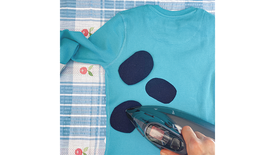 Image of Bluey's blue spots (made of fabric) being ironed on to the back of a blue top.